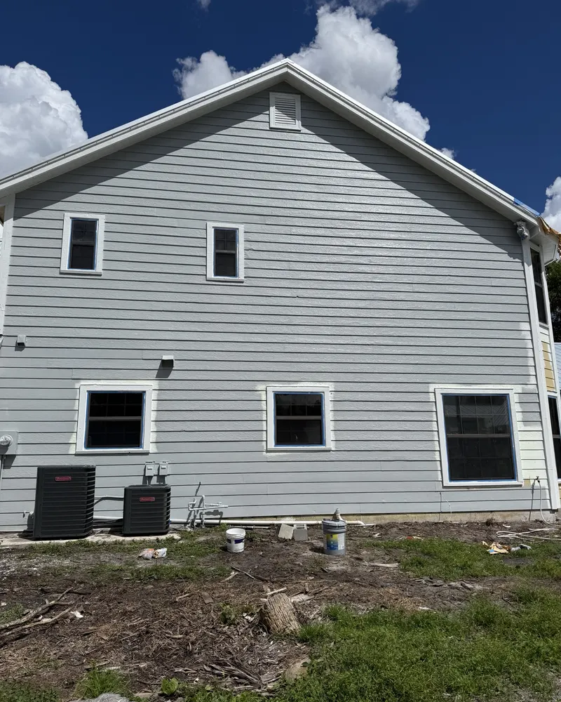After: the same siding repainted light gray with white trim