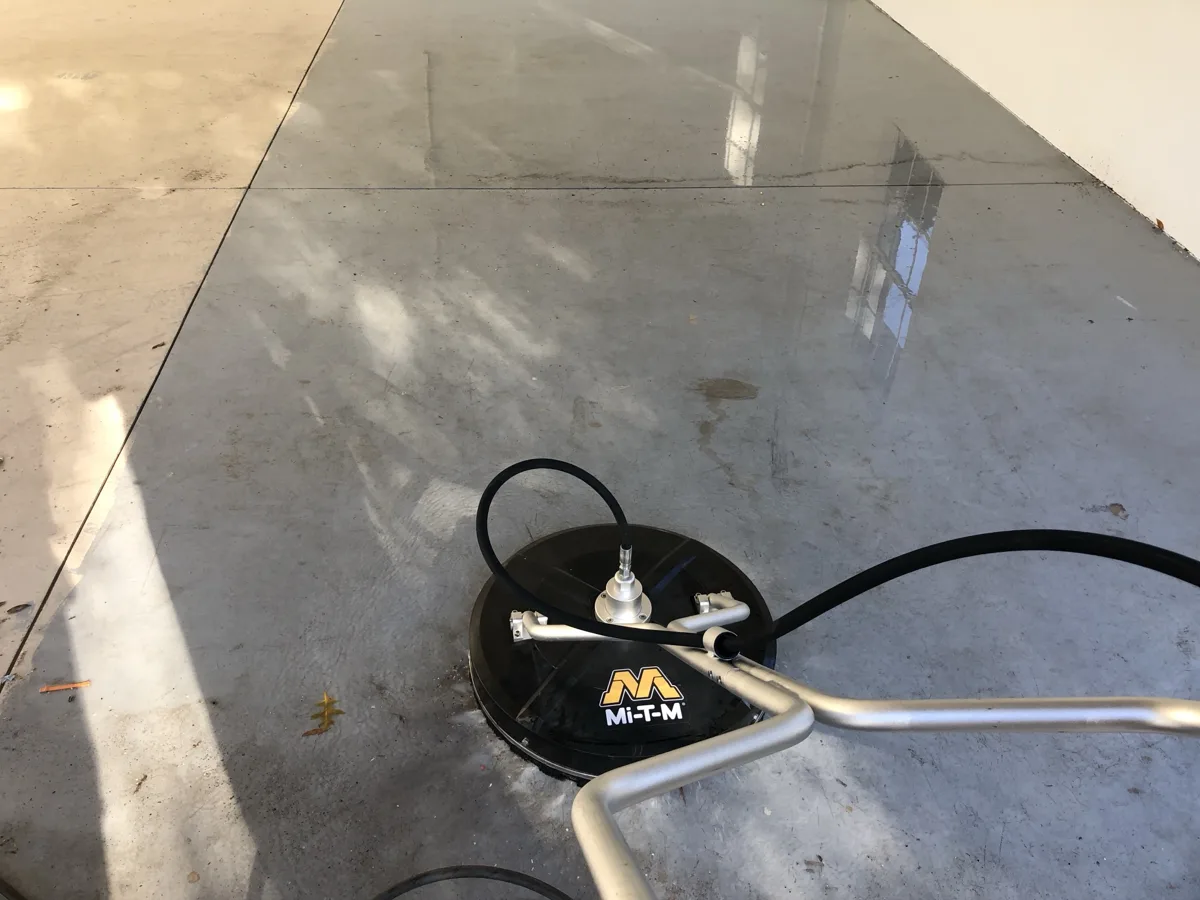 Surface cleaner on a concrete garage floor, with the cleaned area visibly brighter