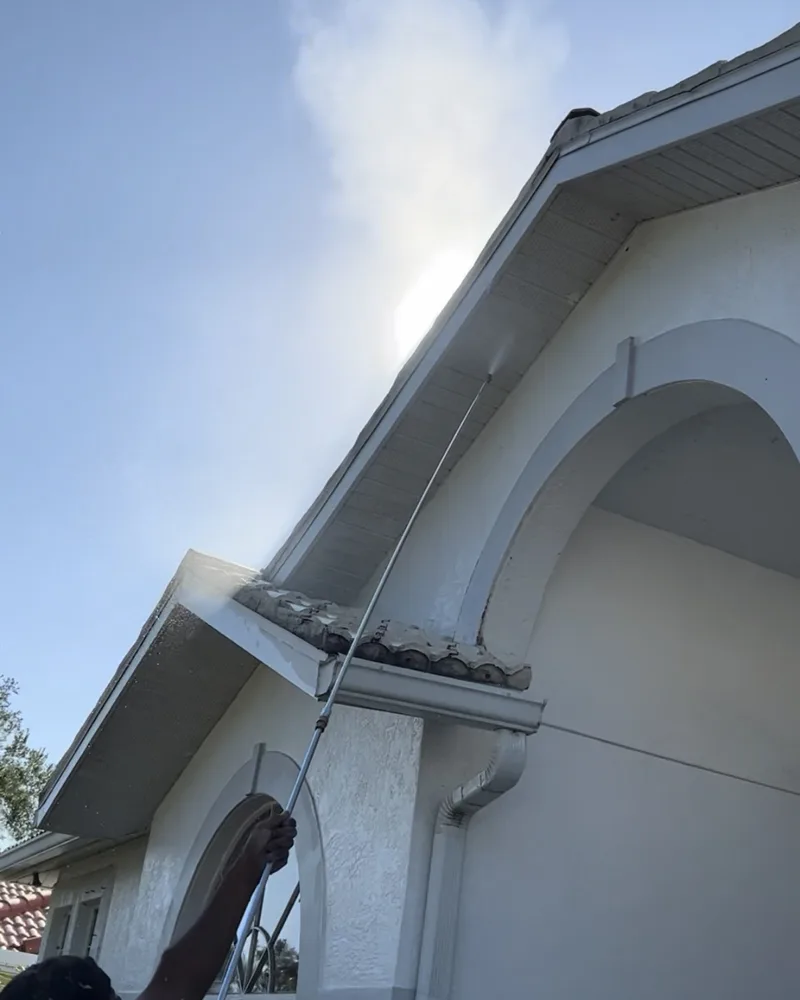 Extension wand washing soffits and fascia on a white stucco home