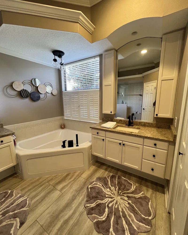 After: white shaker-style vanity and tall cabinets with black hardware in the finished master bathroom