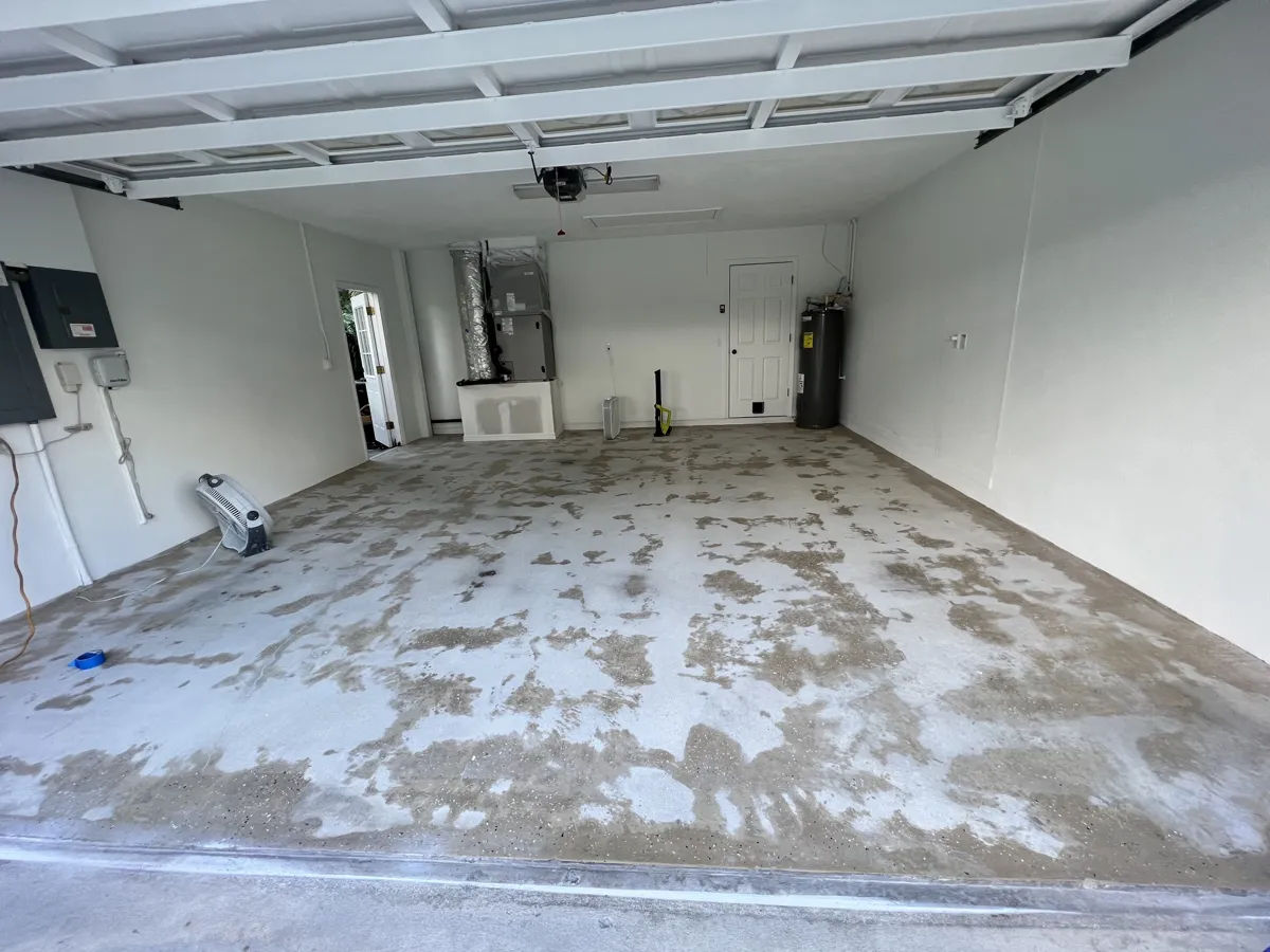 Before: two-car garage floor with the old worn coating partly removed and bare concrete showing