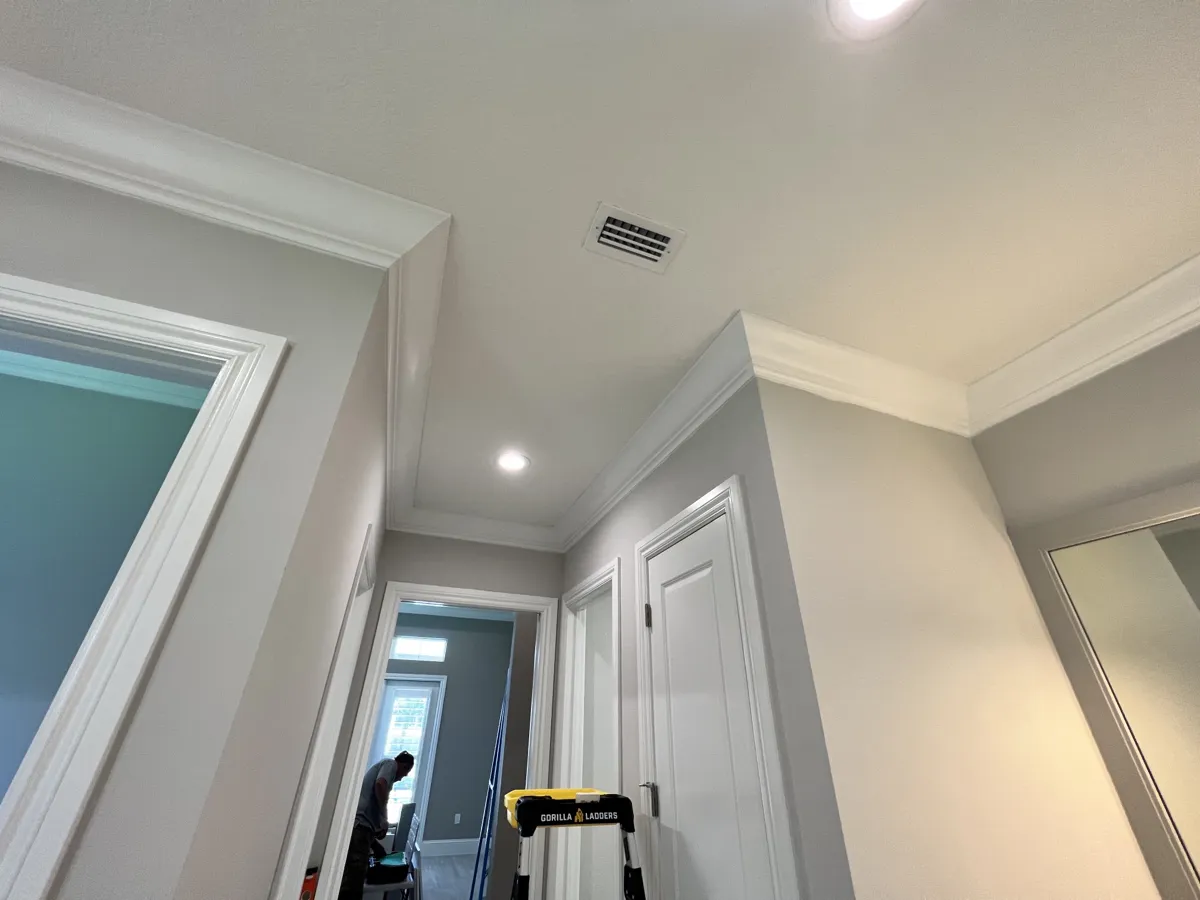 After: hallway with crown molding wrapping the ceiling and white door casings