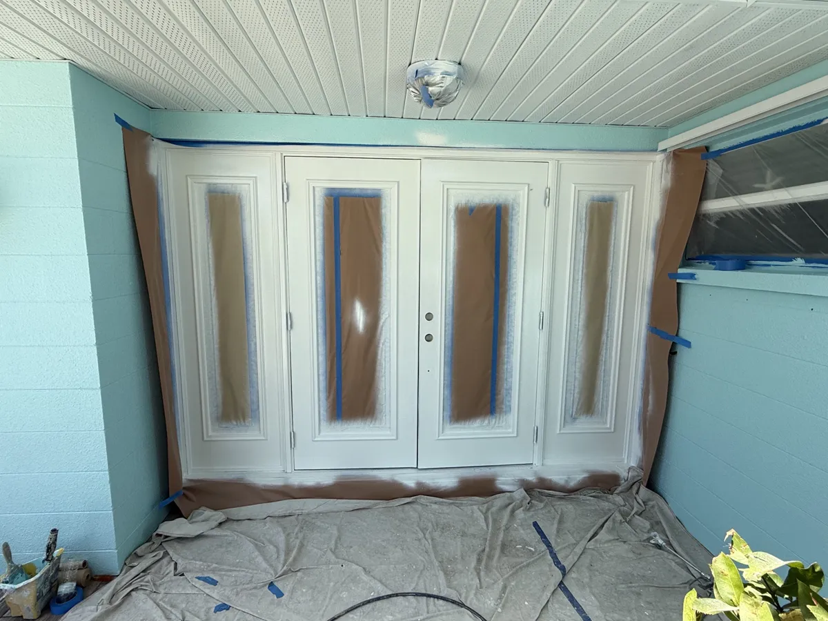 During: double entry doors and sidelites masked with paper and tape and sprayed white
