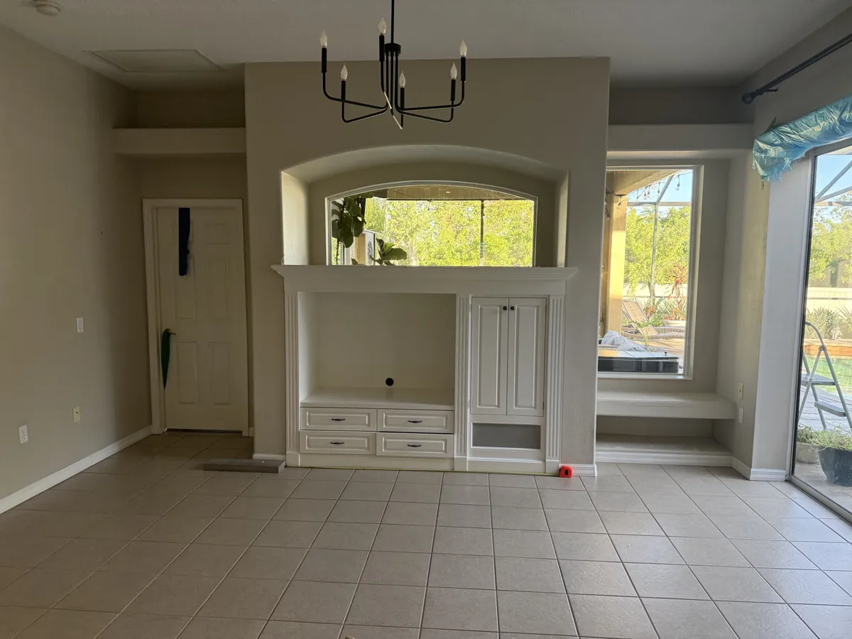 Before: dated built-in entertainment niche with an arched pass-through window and a low bench by the window