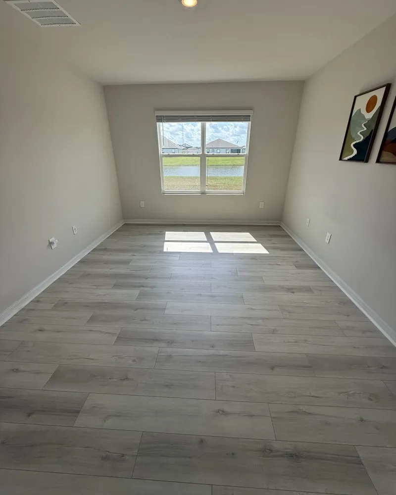 After: the same bedroom with light gray wood-look luxury vinyl plank flooring installed wall to wall