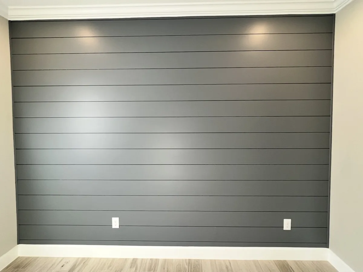 After: the shiplap accent wall painted charcoal gray with white baseboard and crown