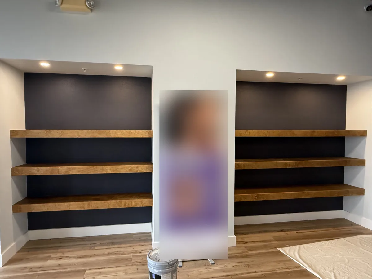 After: thick stained wood floating shelves built into both niches with recessed lights above