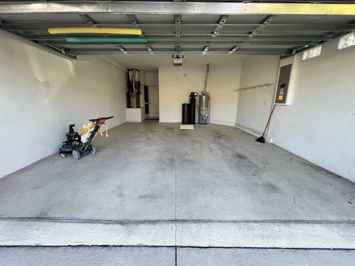 Before: one-car garage with bare stained concrete and the floor grinder ready