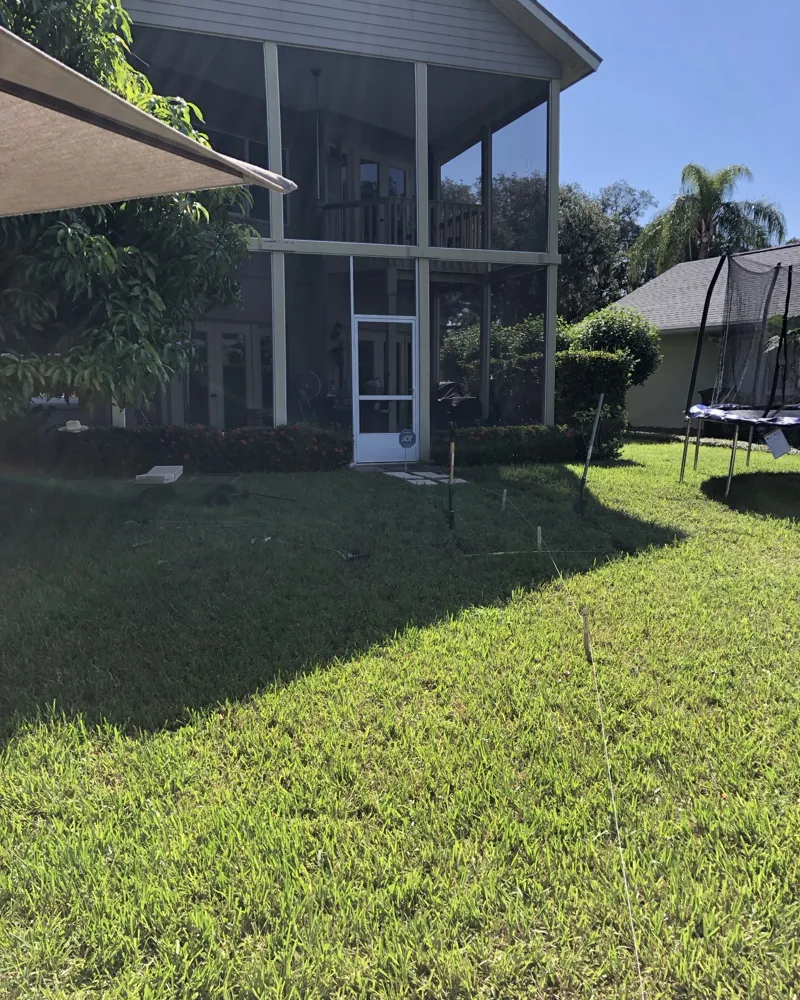 Before: backyard lawn with string lines and stakes laying out a new path to the screened lanai door