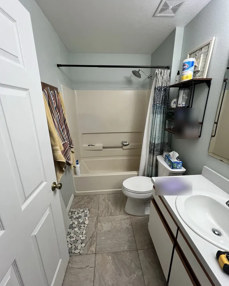 Before: hall bathroom with an old fiberglass tub-shower surround, curtain and dated vanity