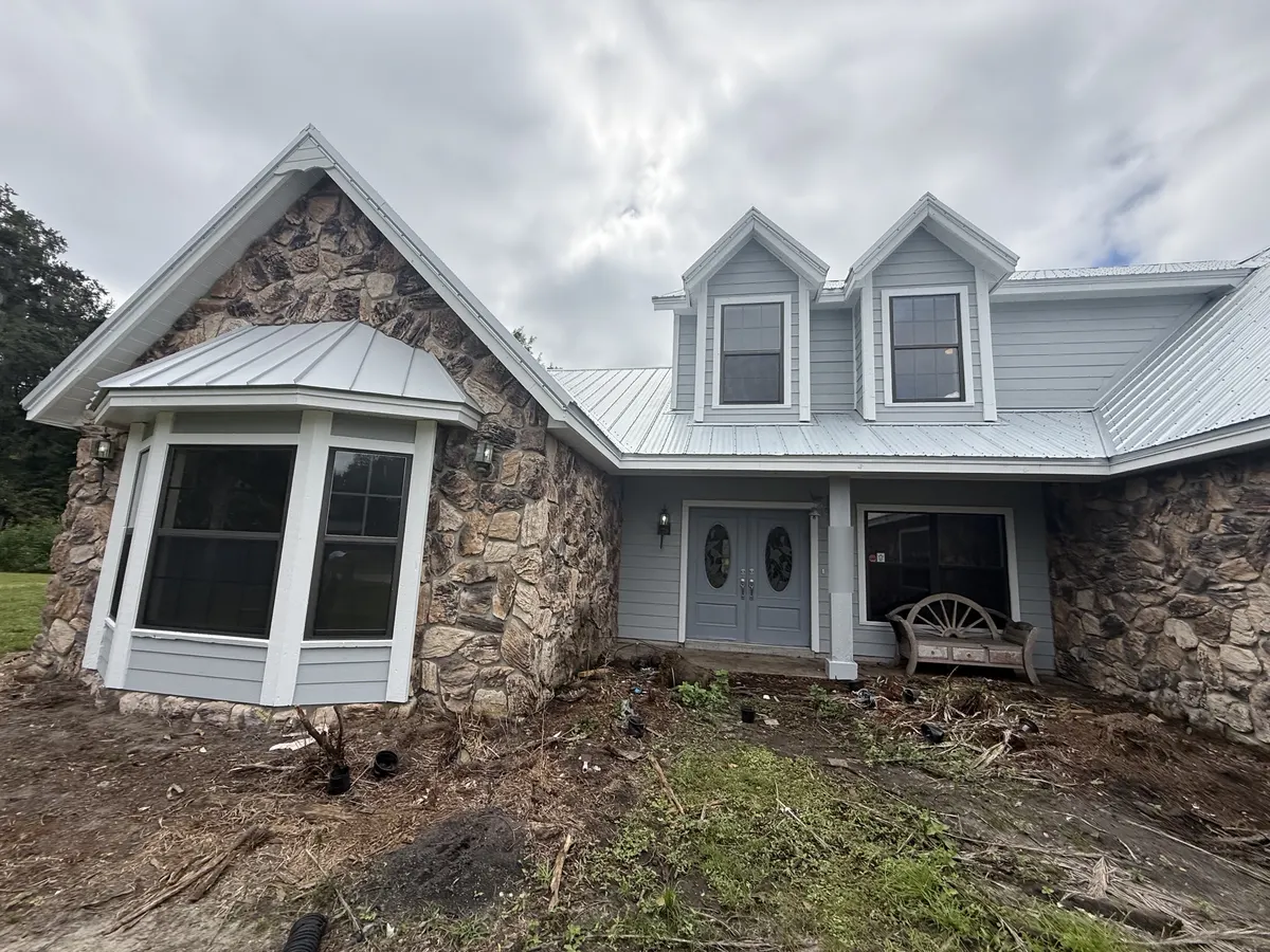 After: the same entry and bay window with light gray siding, white trim and refinished front doors