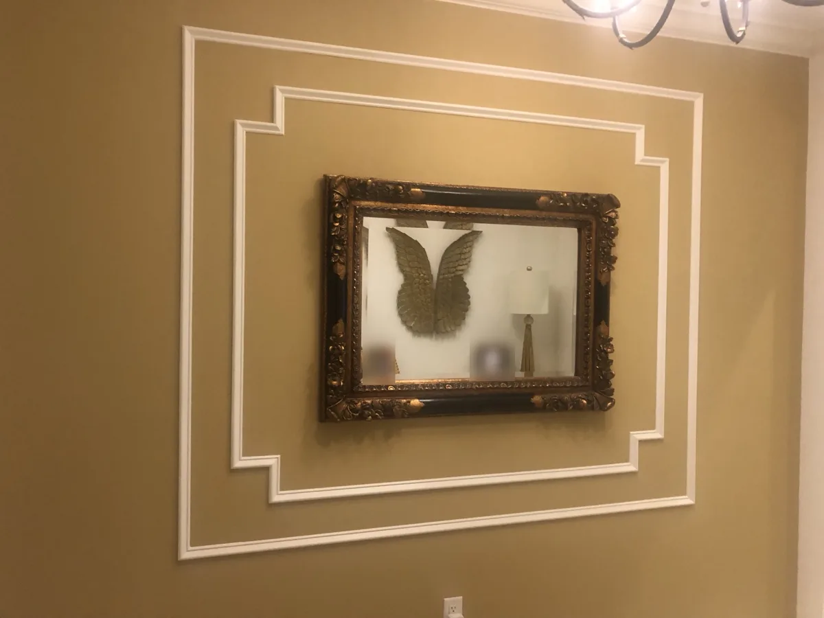 After: white picture-frame molding installed in a double stepped-corner pattern framing the mirror