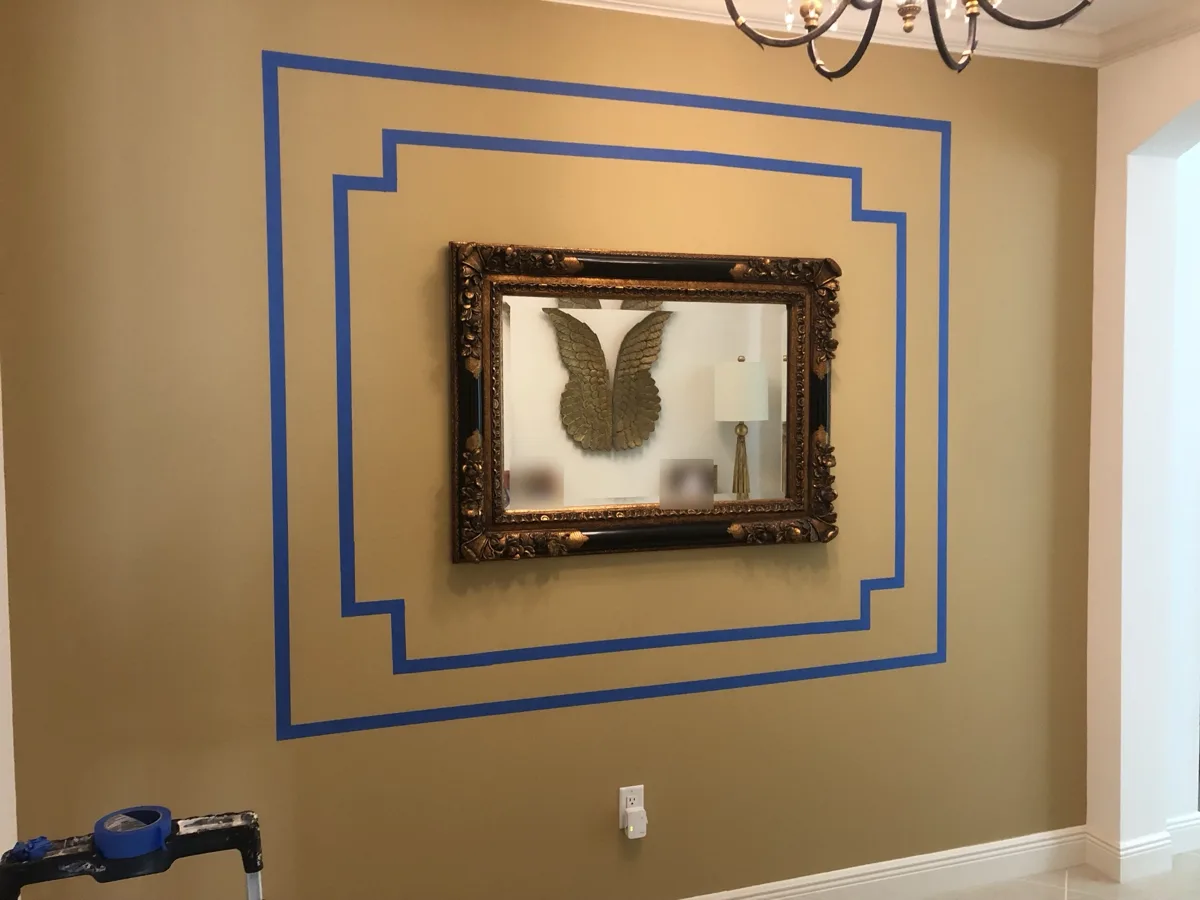 Layout: double picture-frame molding pattern taped out on the wall around a gilded mirror