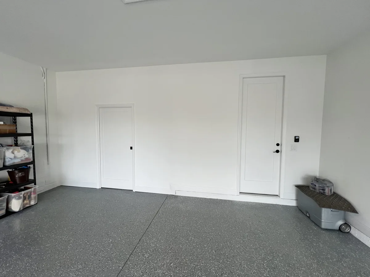 After: finished white wall with a pocket door, casing and baseboard, matching the existing garage wall