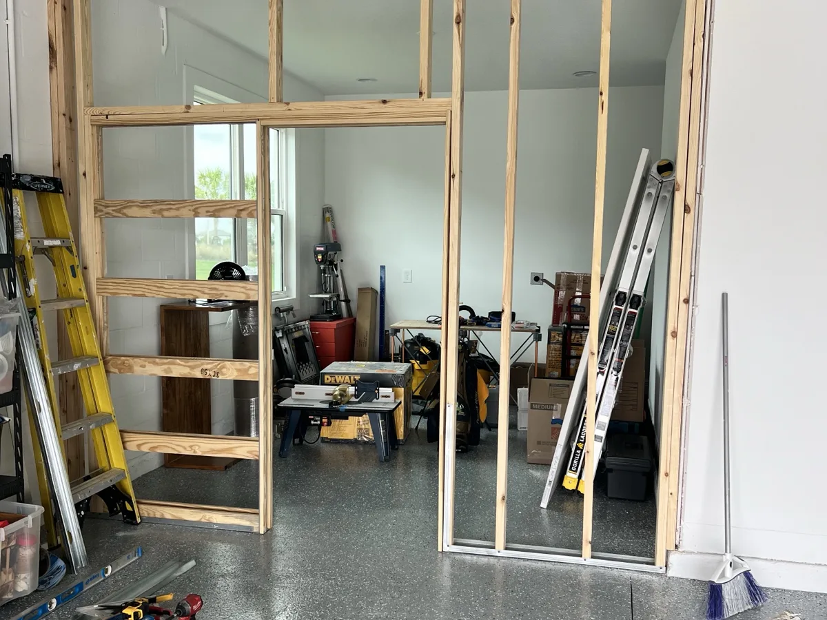 Framing: new wood-framed partition wall with a pocket door frame closing off a workshop area inside a garage
