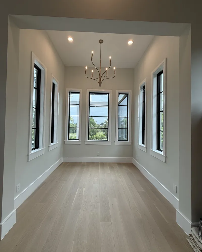 After: finished room with fresh walls, ceiling and crisp white trim around tall windows