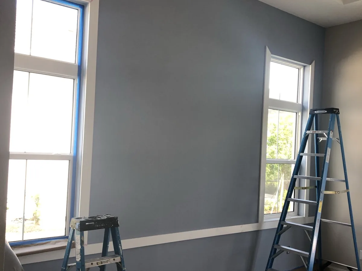 During: blue accent wall painted with the first horizontal trim board installed between two windows