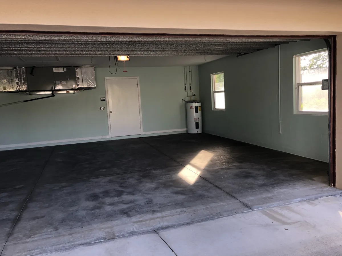 Before: two-car garage with bare, stained concrete floor and freshly painted mint walls