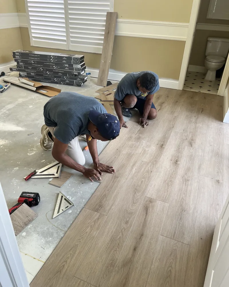 During: two crew members clicking in waterproof luxury vinyl planks over the prepared slab