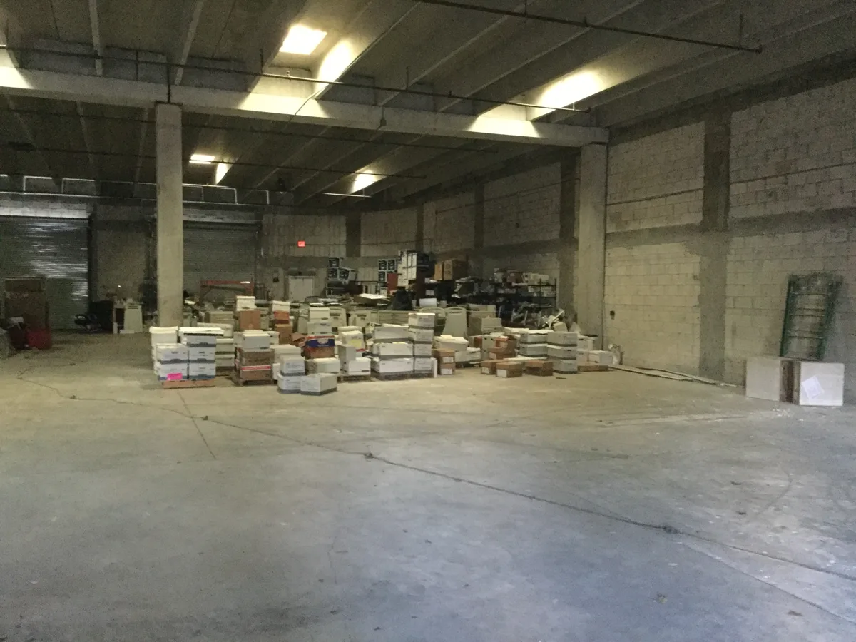 Before: empty warehouse shell with concrete block walls and stored boxes