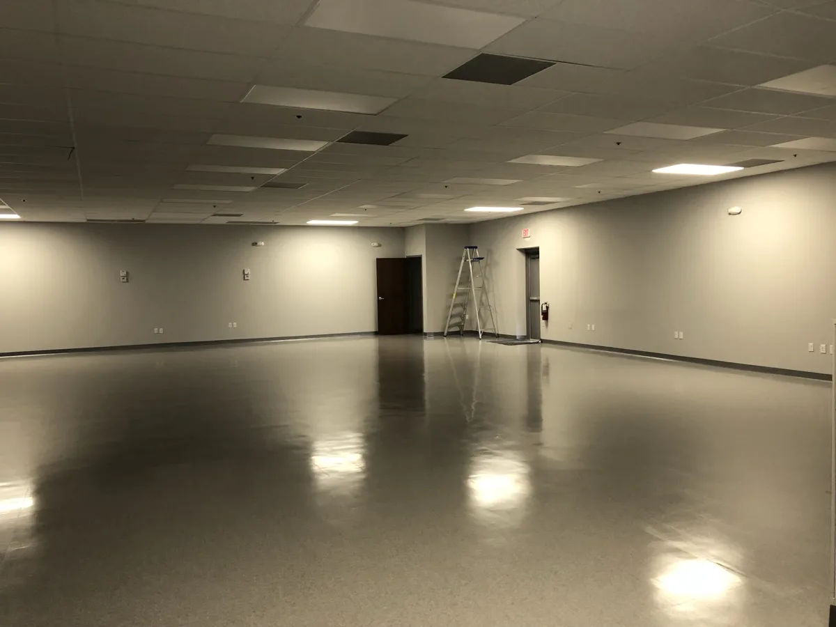 After: large finished commercial room with painted walls, drop ceiling and polished floor