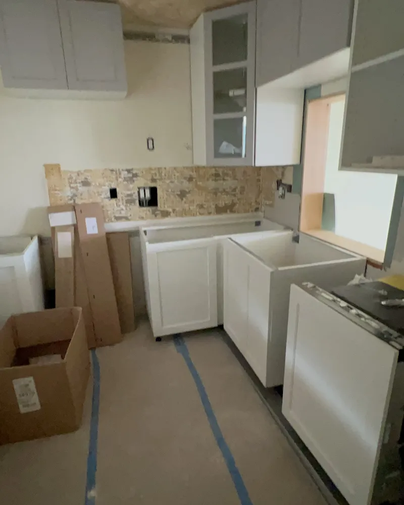 During: new white shaker base cabinets and gray upper cabinets being installed