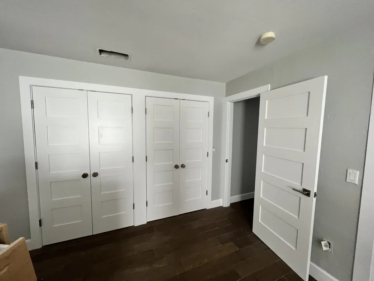 After: new five-panel shaker double closet doors and matching bedroom door with new trim and hardware