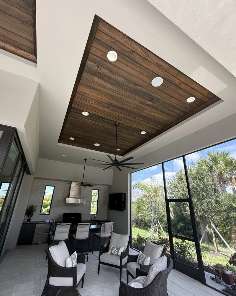 Lanai tray ceiling clad in tongue-and-groove wood planks with a rich sealed finish over the outdoor kitchen
