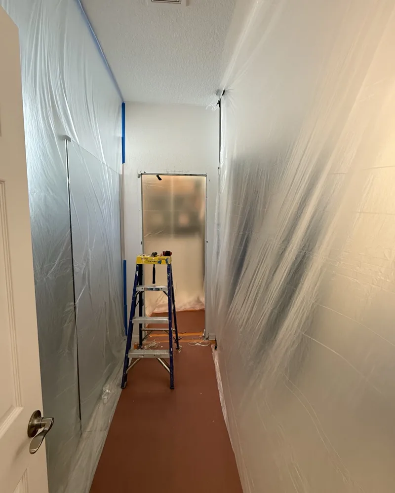 Process: hallway sealed off with plastic dust containment and floor protection while the opening is reframed