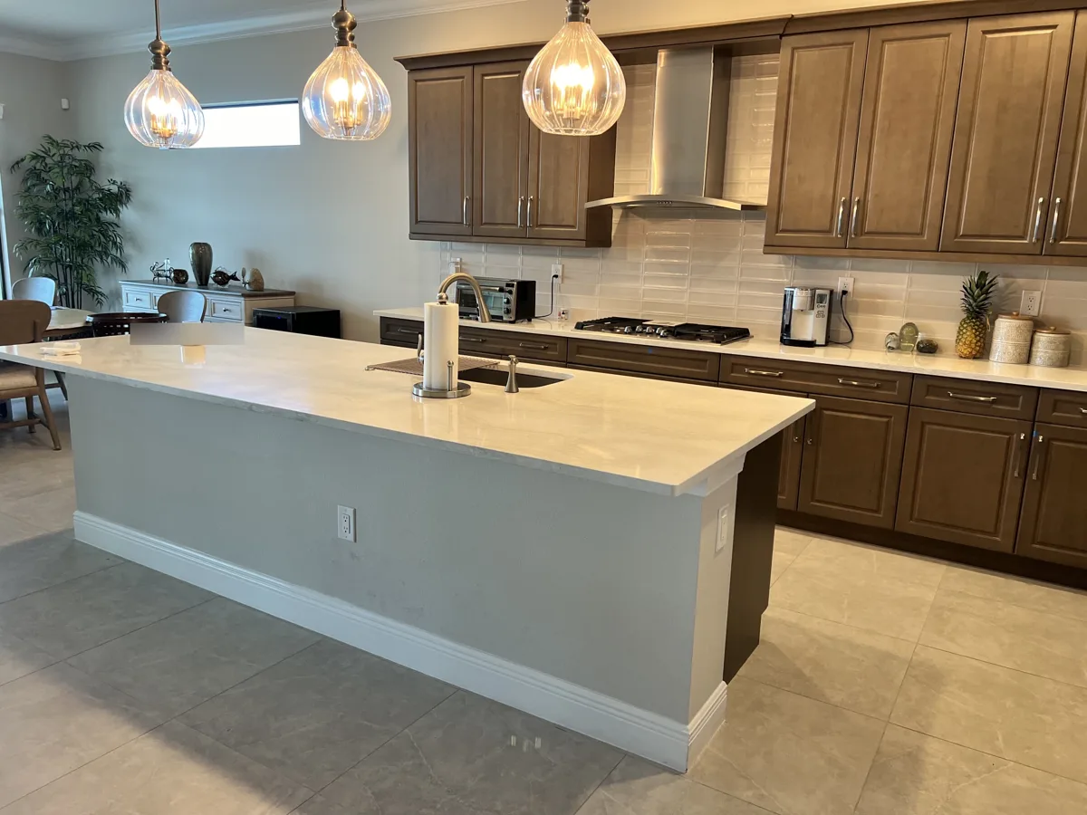 Before: kitchen island with plain gray painted drywall sides and white baseboard, not matching the brown cabinets