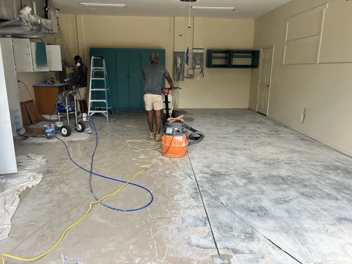 Process: crew diamond-grinding the garage floor with dust extraction while cabinets are spray-painted, with yellow walls and teal cabinets before the update