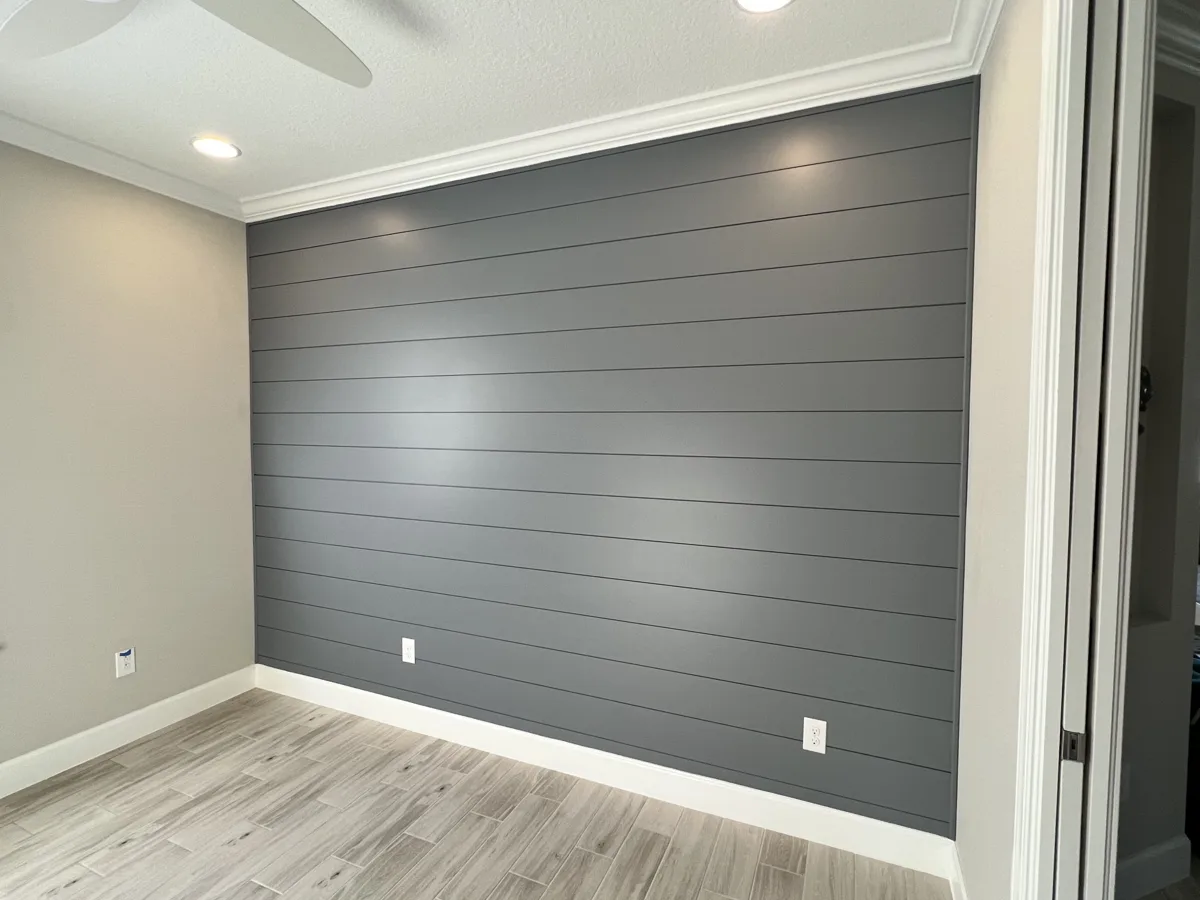 Bedroom shiplap accent wall painted charcoal gray with white crown and baseboards in Palmetto