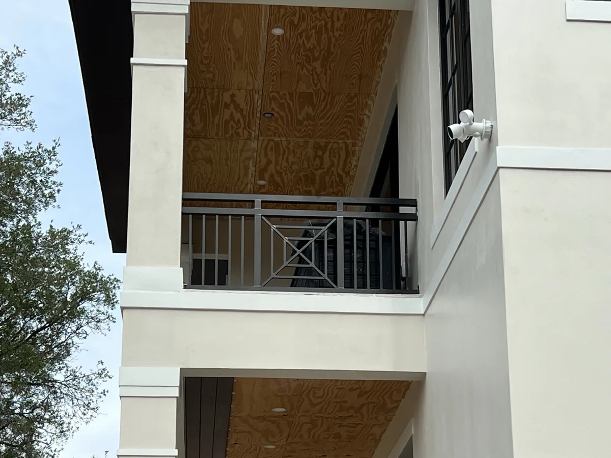 Before: bare plywood ceilings on a two-story front porch and balcony of a new home