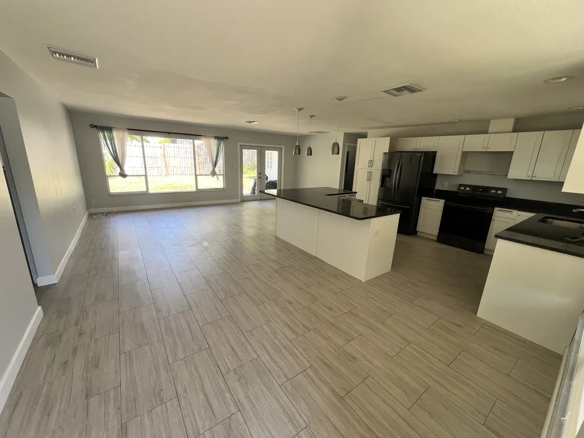 After: the same open living area and kitchen with a smooth, repaired ceiling and fresh paint