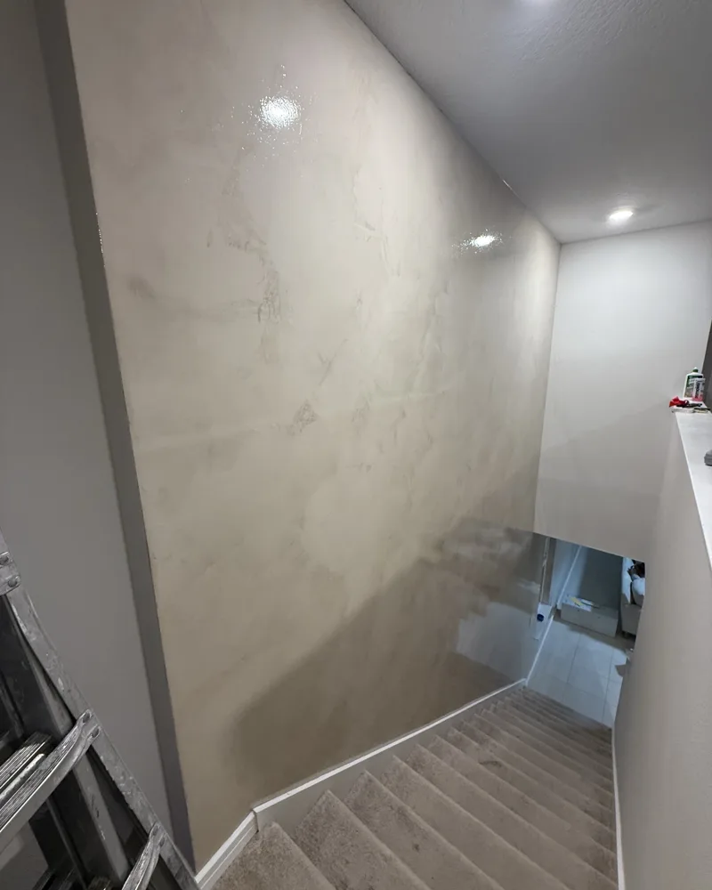 After: full-height stairwell wall finished in polished microcement with a soft sheen