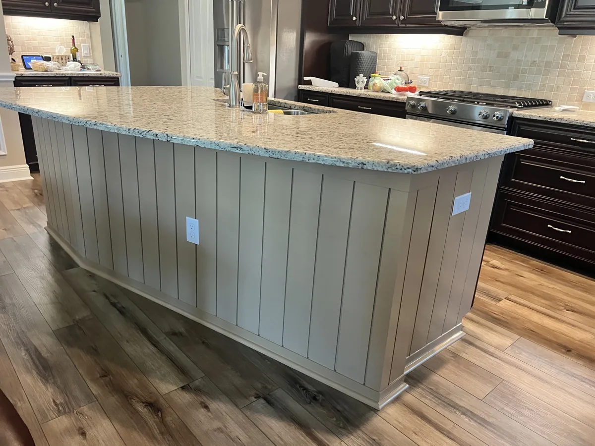 After: kitchen island clad in vertical shiplap and painted a warm taupe under the granite countertop
